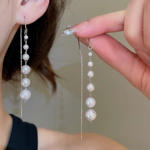 Detail of silver drop earrings with a gradient of five white pearls on long delicate chain