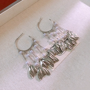 Detailed close-up of metallic fishtail tassel earrings with elegant imitation pearls