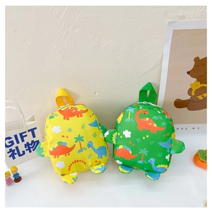 Detail view of mini children backpacks in yellow and green with cartoon dinosaur patterns