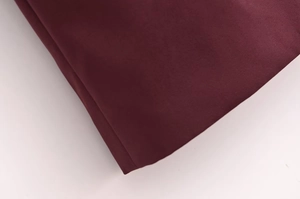 Vue macro détaillée de la texture du tissu bordeaux et des coutures fines du manteau