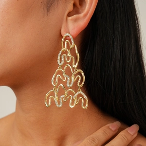Macro shot of large fluid metal wavy drop earrings with glittering pavé rhinestones