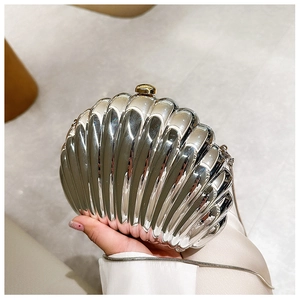 Detail of silver shell-shaped clutch bag with textured finish and thin metal chain strap