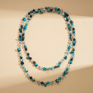 Detailed view of layered blue shell beads and crystal beads necklace on beige stairs