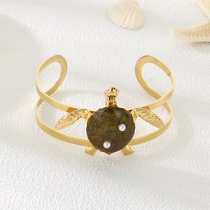 Detailed close-up of golden sea turtle bangle with brown marble shell and white pearls