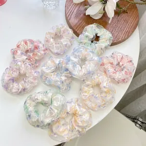 Flache Ansicht von bunten Chiffon-Haargummis mit Blumenmuster auf Holztablett