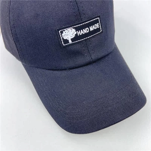Detail view of navy blue cotton baseball cap with Hand Made patch and fine stitching