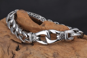 Macro detail of men's vintage stainless steel chain bracelet on a textured wood background