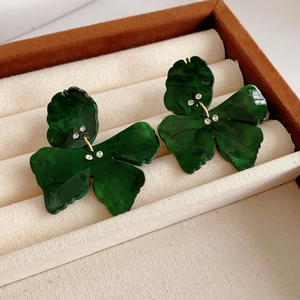 Close-up of retro green resin bow earrings with marble texture and crystal studs