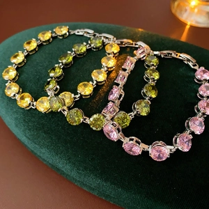 Detail of round cut zircon tennis bracelets in yellow, green, and pink on velvet box