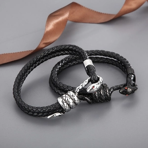 Detail showing snake head clasps on braided leather bracelets with red crystal eyes