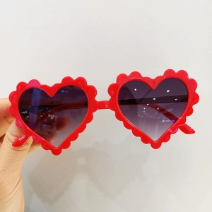 Vue détaillée des lunettes de soleil coeur pour enfants avec monture rouge à bords ondulés