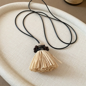 Detailed macro view of retro ethnic style straw broom pendant with wooden beads
