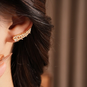 Detail of ear cuff with zircons and pearls worn by a model for a luxury look