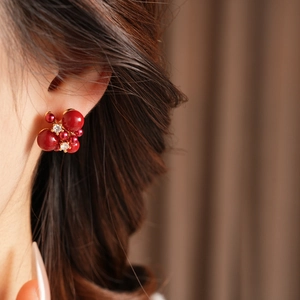 Primo piano dell'orecchino a fiore con zircone rosso indossato in uno stile retrò