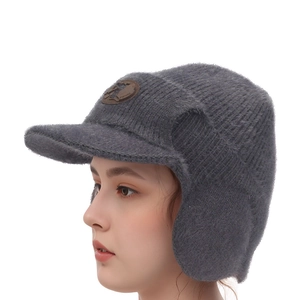 Détail du bonnet en tricot gris avec cache-oreilles et écusson en cuir pour l'hiver
