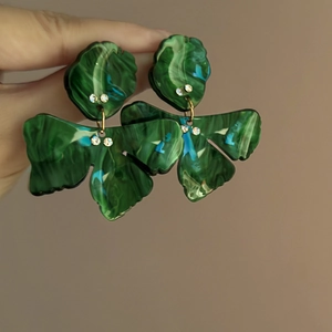 Detail of dark green marble resin earrings with small crystals and leaf-shaped pendants