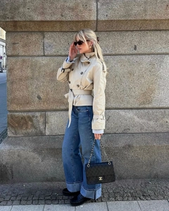 Detail of short beige trench coat with double-breasted buttons and belt buckle details