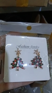 Detailed view of colorful rhinestone Christmas tree earrings on white display card