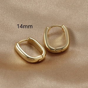 Macro detail of 14mm gold-plated U-shaped earrings on elegant champagne silk fabric