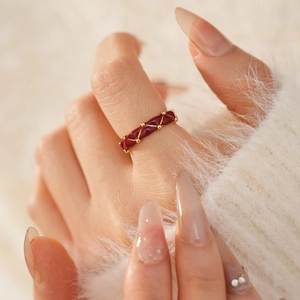Close-up of gold-plated quilted ring with burgundy enamel and micro beads on hand