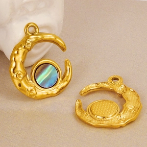 Detailed macro view of golden crescent moon pendant with iridescent shell inlay on beige background