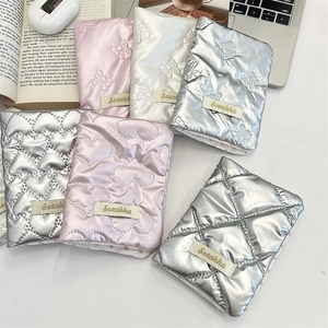 Flat lay of quilted bow passport holders in silver, pink and white with satin finish