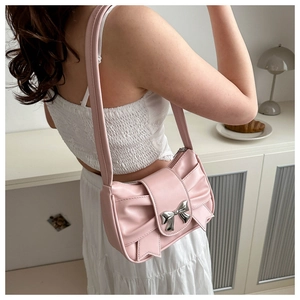 Elegante borsa sottobraccio rosa con fiocco in metallo indossata da modella in interni