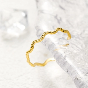 Close-up of golden 18K gold-plated wave-textured ring on crystal ice cube background