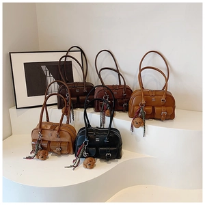Close-up of five vintage leather pillow bags with front pockets and teddy bear charms