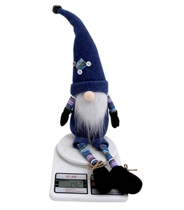 Blue Christmas gnome plush toy on an electronic scale showing a weight of 142 grams
