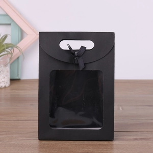 Detail of black gift bag with clear window and ribbon on a wooden surface