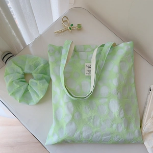 Close-up of light green pleated canvas tote with white polka dots and matching hair scrunchie