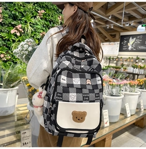 Detail of check pattern backpack with plush bear patch and cute rabbit charm pendant