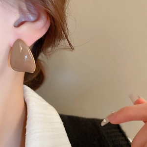 Macro shot of minimalist teardrop stud earrings in warm brown enamel on model ear