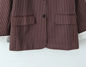 Detail of dark brown striped blazer showing flap pockets and folded white cuffs
