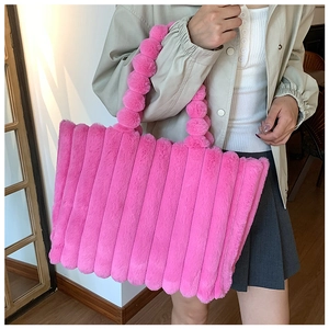 Detail of plush bright rose pink tote bag with fuzzy ball handle and striped texture