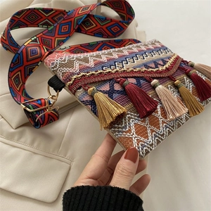 Detail of bohemian woven bag featuring colorful fringe and geometric wide strap