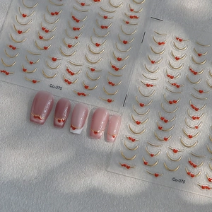 French style gold nail stickers with red hearts and fine lines on a grey stone surface
