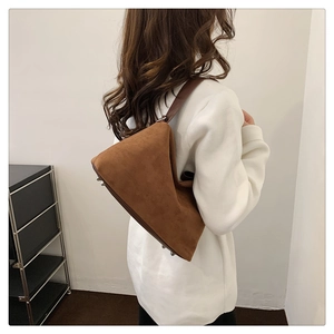 Vue détaillée d'un sac à bandoulière en daim marron avec sangle en cuir sur un modèle