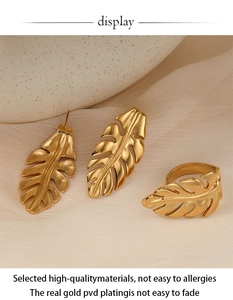 Detail of gold PVD plated stainless steel monstera leaf ring and earrings set