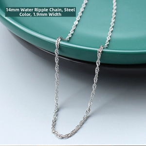 Detail of 1.9mm water wave chain in steel color draped over a dark green plate edge