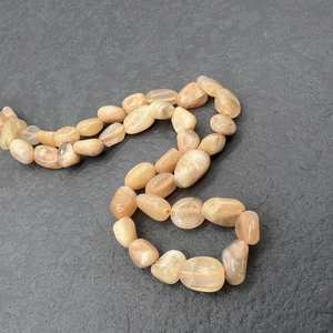 Macro detail of irregular peach moonstone beads with natural texture on stainless steel necklace