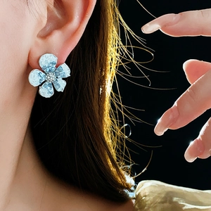 Close-up of blue crystal flower earrings with rhinestones on a female model