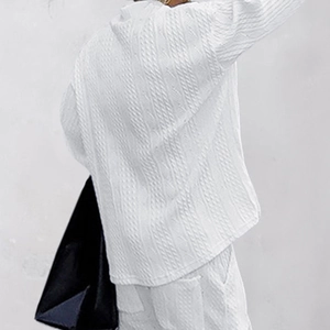 Detail view of white men's knitted sweater showing the textured jacquard fabric pattern