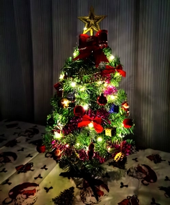 Mini decorated Christmas tree featuring red bows, ornaments and warm LED lights