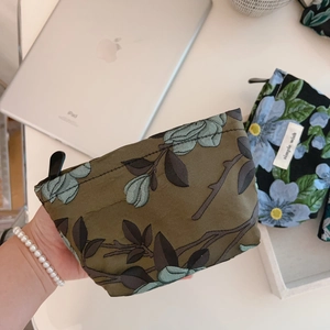 Detail of dark green floral jacquard mini pouches with black zipper closure