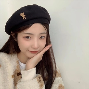 Detail of black wool beret with cute brown 3D teddy bear charm decoration