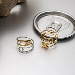 Detail of silver and gold safety pin rings with adjustable open band and polished metal