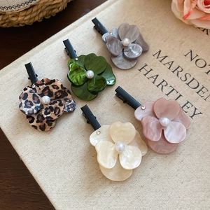 Détails des barrettes à fleurs en résine avec perles sur un fond en toile beige