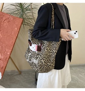 Detail of leopard print tote bag with dog embroidery worn as a shoulder bag